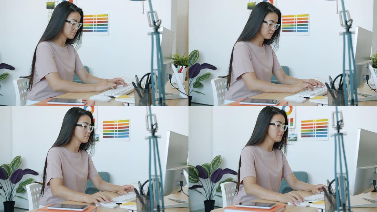 美丽的亚洲女性设计师在办公室室内使用电脑打字的肖像