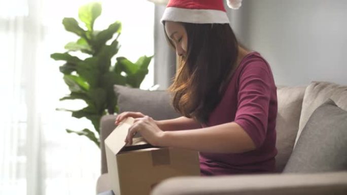 在圣诞节活动中，亚洲妇女在家中收到包裹和打开盒子