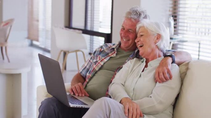 高级高加索夫妇坐在家里的沙发上在笔记本电脑上进行视频通话