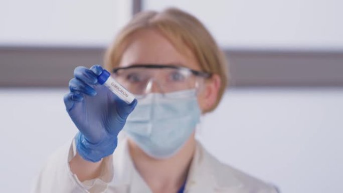 女实验室研究人员穿着个人防护用品，手持标有欧米克隆标签的试管