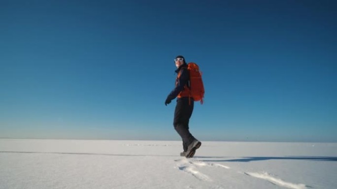 那个年轻的女人背着背包徒步穿越雪场。慢动作