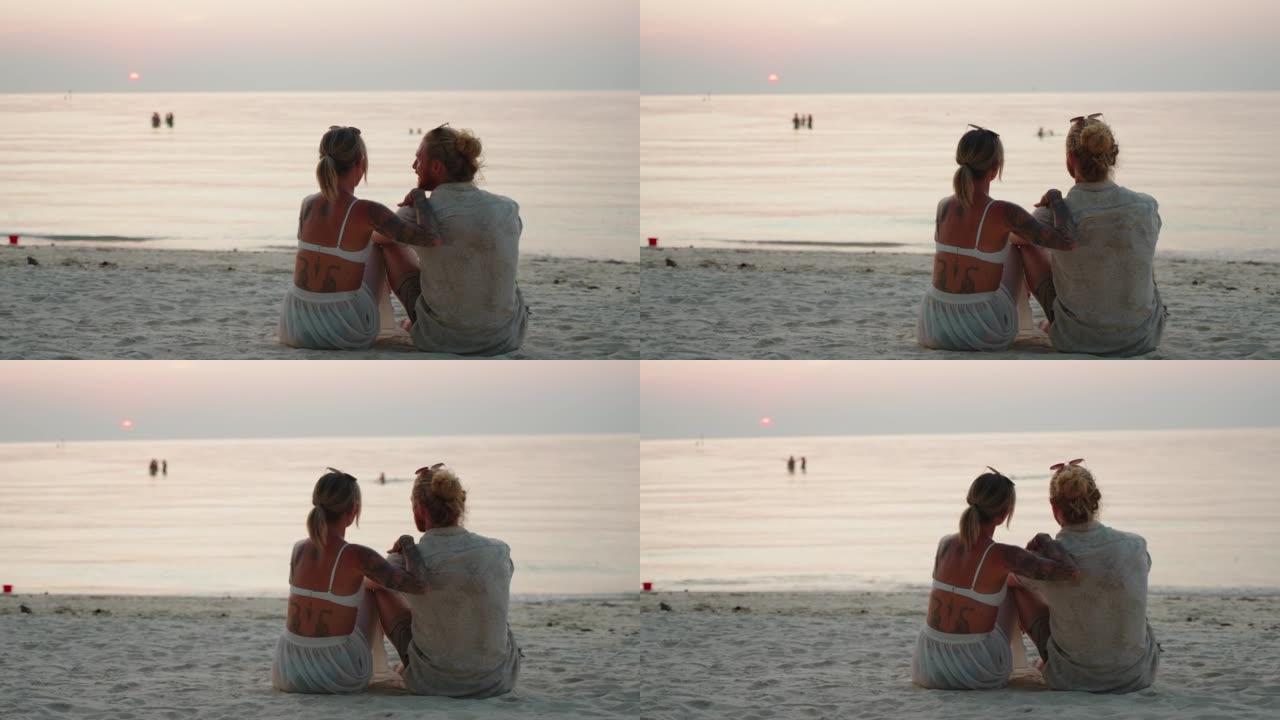 享受日落的夫妇情侣夫妻坐在沙滩上的背影