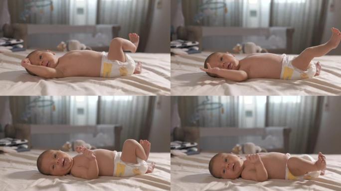 躺在床上的尿布中可爱的新生婴儿的肖像。活跃的幼儿交流和咕咕叫。天真的大眼睛充满了惊奇，环顾四周，发现