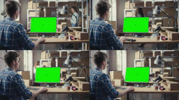 年轻人使用带有绿屏Chromakey模拟显示器的台式计算机。分销经理和在分销仓库工作的员工用纸箱。在