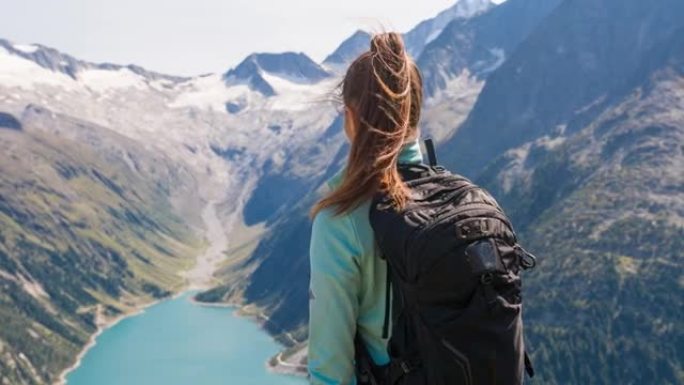女徒步旅行者站在山顶上，欣赏山谷湖的壮丽景色