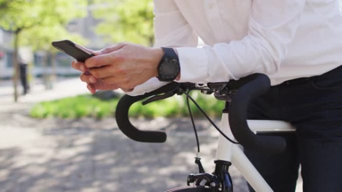 男子在街上倚着自行车时使用智能手机的中段