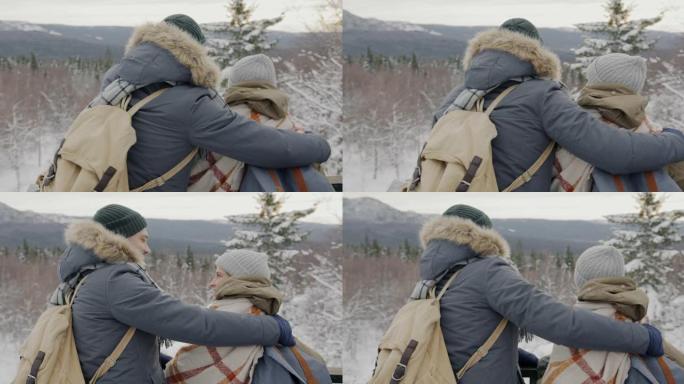 相爱的夫妇看着冬天的风景指着群山讨论一起徒步旅行的景色