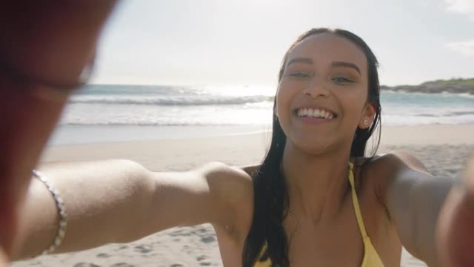 年轻的混血女子在海滩上视频聊天女孩在相机上吹吻分享暑假使用智能手机展示旅游冒险度假乐趣