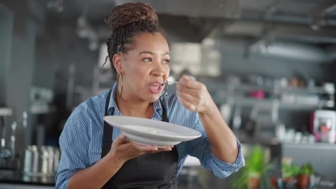 餐厅厨房: 黑人女厨师准备菜肴，品尝食物并享受美食的肖像。专业烹饪美味、正宗、传统食品，使用健康食材