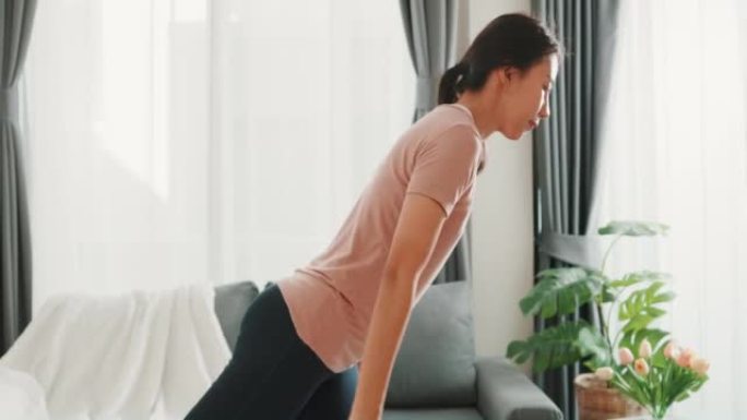 年轻迷人的强壮美丽的健身女孩亚洲女人穿着运动服练习在家里的客厅为初学者做锻炼。