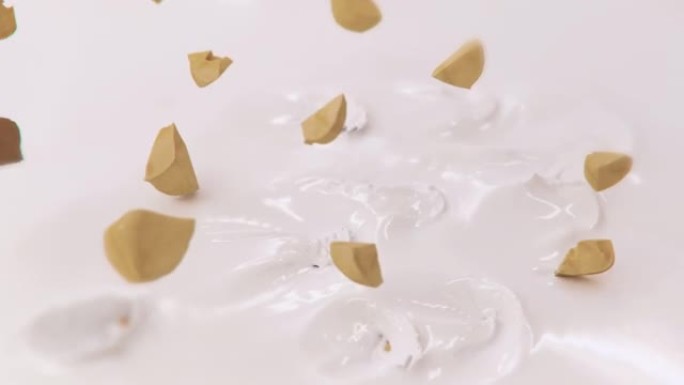 榛子碎片在4k超慢动作中溅到液体奶油中