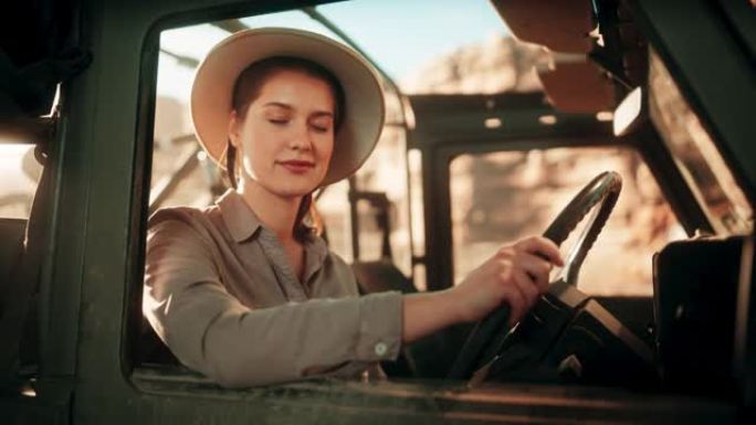 沙漠之旅: 美丽的女探险家的肖像，从汽车司机的窗户向外望去，微笑着。女冒险家乘坐越野SUV穿越峡谷。