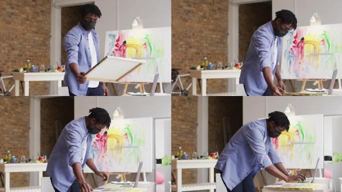 非裔美国男艺术家在art studio使用笔记本电脑戴口罩