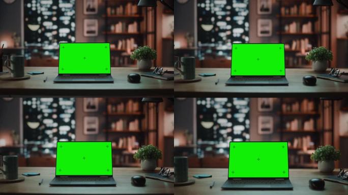 笔记本电脑，带有模拟绿屏显示屏，站在舒适的客厅的桌子上。在背景时尚的现代家庭办公室工作室，晚上有大的