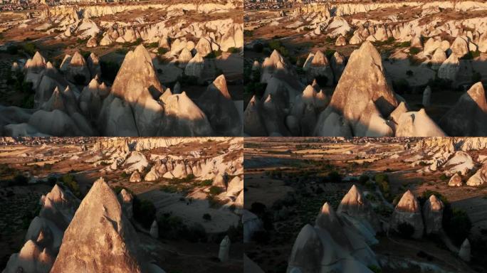 夏季日落时，在卡帕多西亚土耳其，无人驾驶飞机在大气美丽的高大白色岩石景观周围平移。