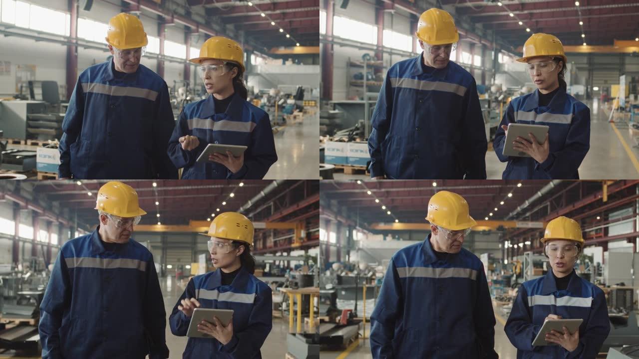 带平板电脑的女工厂主管与新工人交谈