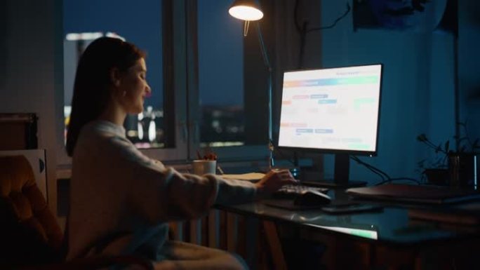 女经理晚上在Dark Loft办公室的Creative Agency的台式计算机上工作。翻新的时尚设