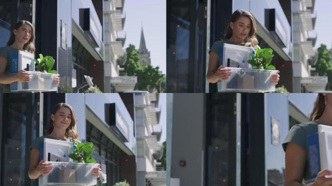 4k视频片段，一名年轻的女商人带着装满她的物品的盒子离开办公室