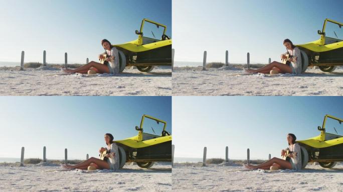 快乐的高加索女人坐在海边的沙滩车旁边弹吉他