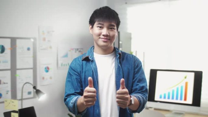 自信的肖像亚洲商人站在办公室竖起大拇指