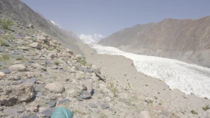 自由旅行者的后视图穿着冬季夹克，背着黄色背包的年轻女性坐在岩石上，早晨可以看到冰川的景色。体验式旅行