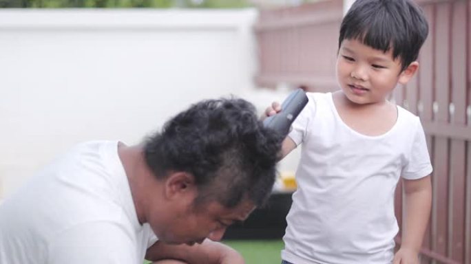 儿子在新型冠状病毒肺炎大流行期间在家用电动剃须刀剪掉父亲的头发