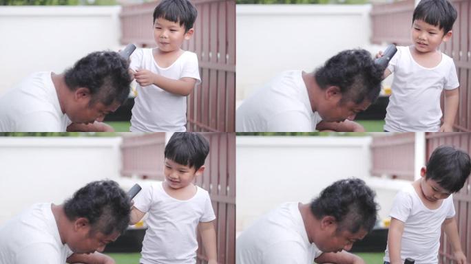 儿子在新型冠状病毒肺炎大流行期间在家用电动剃须刀剪掉父亲的头发