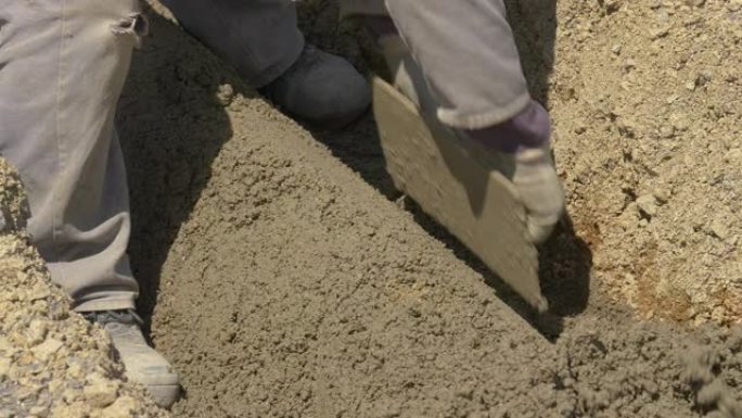 特写: 承包商使用刮铲和湿混凝土来覆盖污水管道