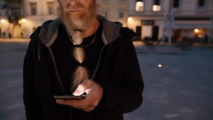 晚上在城市中使用智能手机的胡须女士无法辨认的男人
