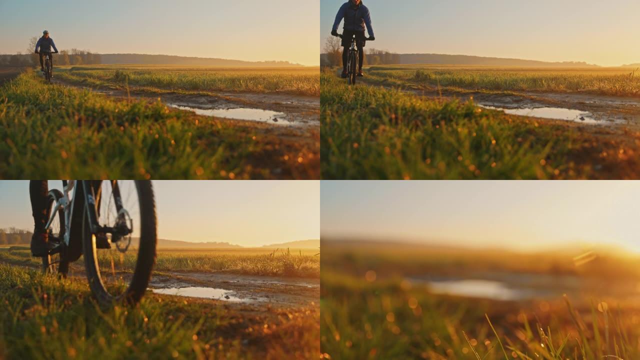 日落时分，SLO MO MTB骑自行车的人在草地之间的小路上骑着泥泞