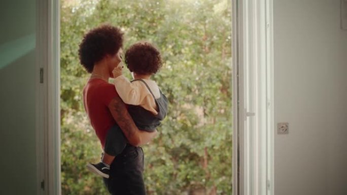 爱的混血儿家庭在现代家庭客厅拥抱和抱着可爱的男婴，看着阳台。开朗的母亲养育孩子。童年、新生活、为人父