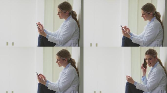 穿着白大褂的女医生坐在医院走廊里用手机拍摄慢动作