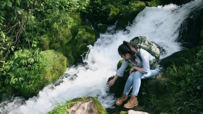 坐在瀑布边的女徒步旅行者休息一下
