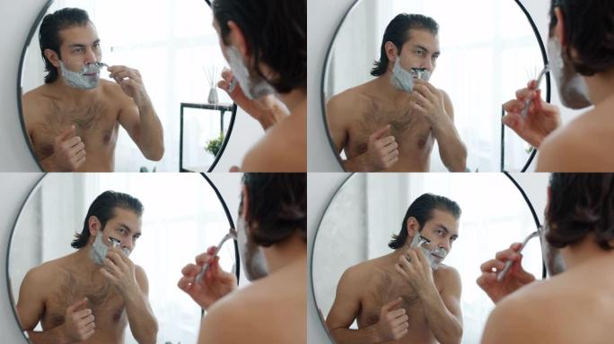 迷人的家伙在浴室里赤裸上身站在镜子上刮胡茬