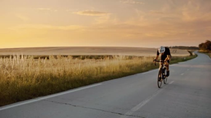 SLO MO成年自行车手在日落时快速驶过乡村