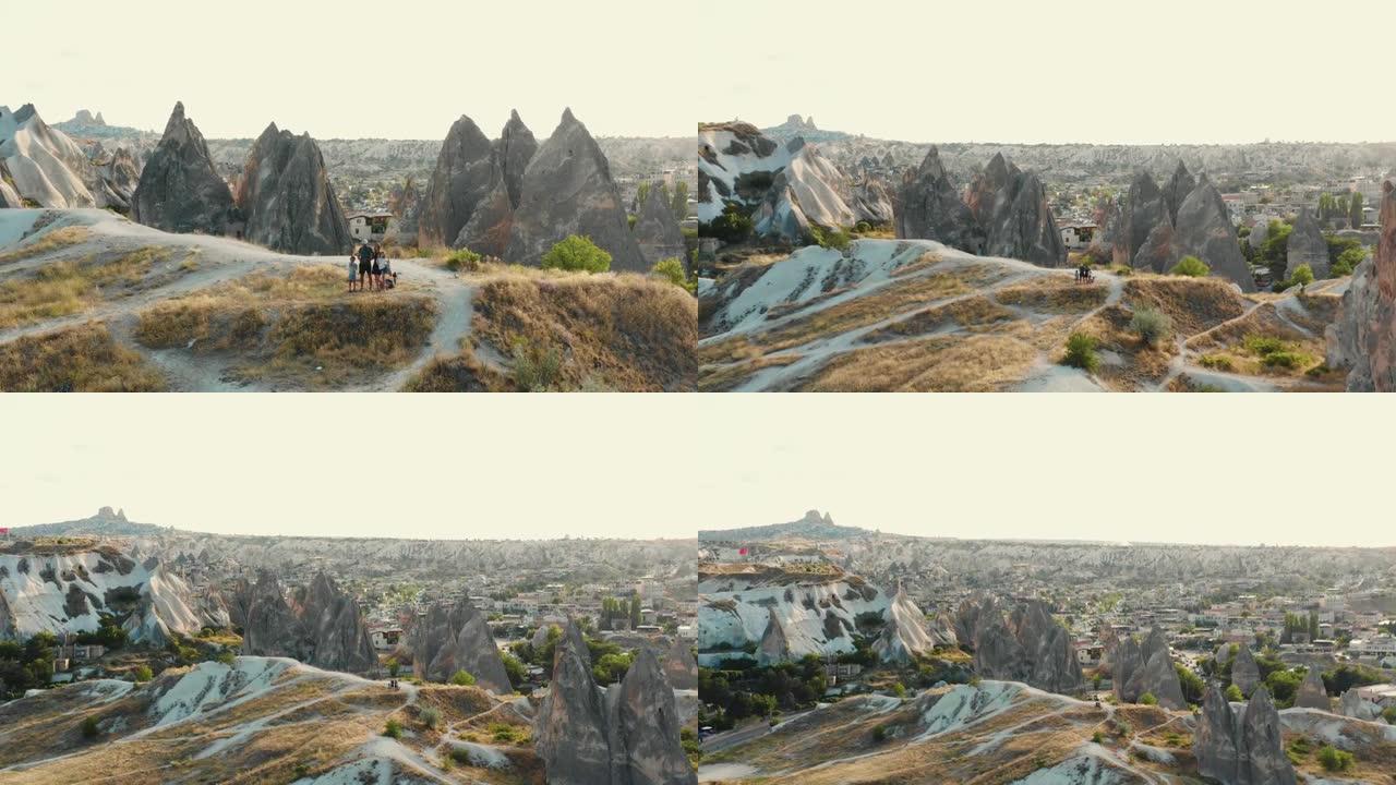 无人机飞离幸福的家庭，孩子们站在惊人的大石头上欣赏史诗般的景色，山脉全景。