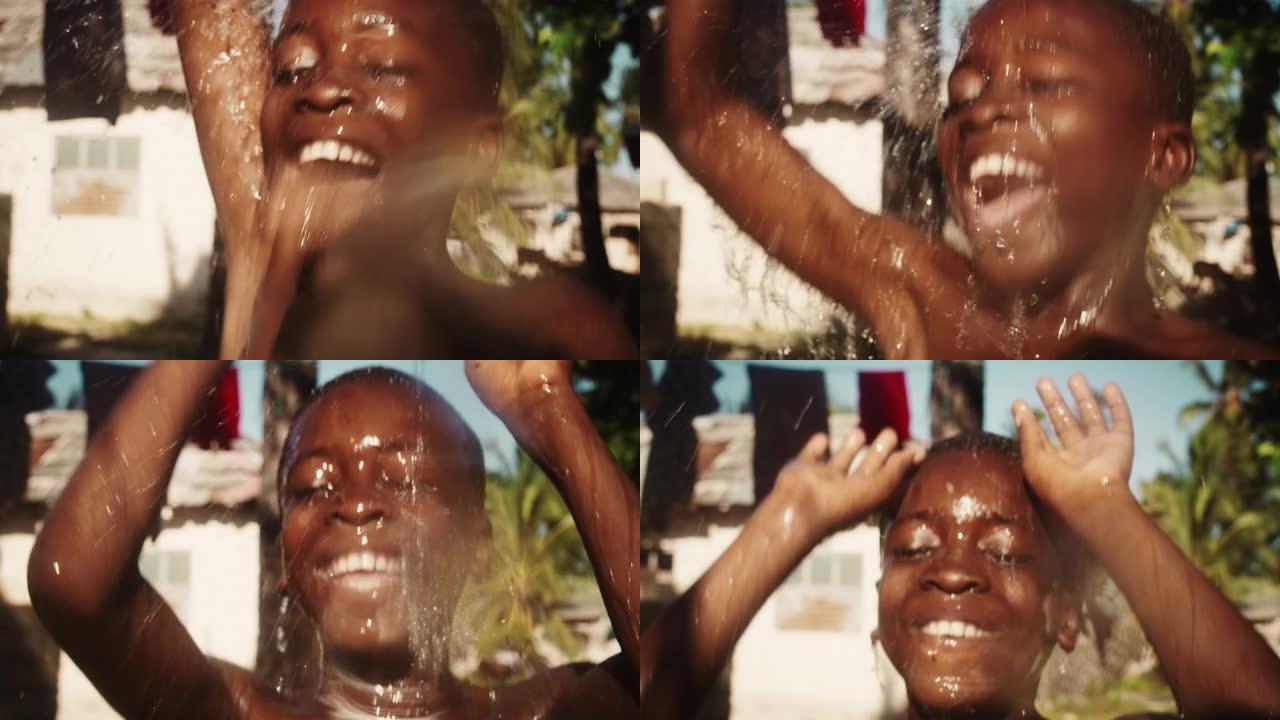 美学慢动作特写:真实的非洲男孩在倒水下跳来跳去的肖像。在漫长的干旱和炎热的天气后，快乐和感激的孩子享