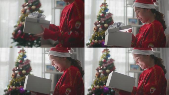 女人在圣诞节用红丝带解开礼品盒