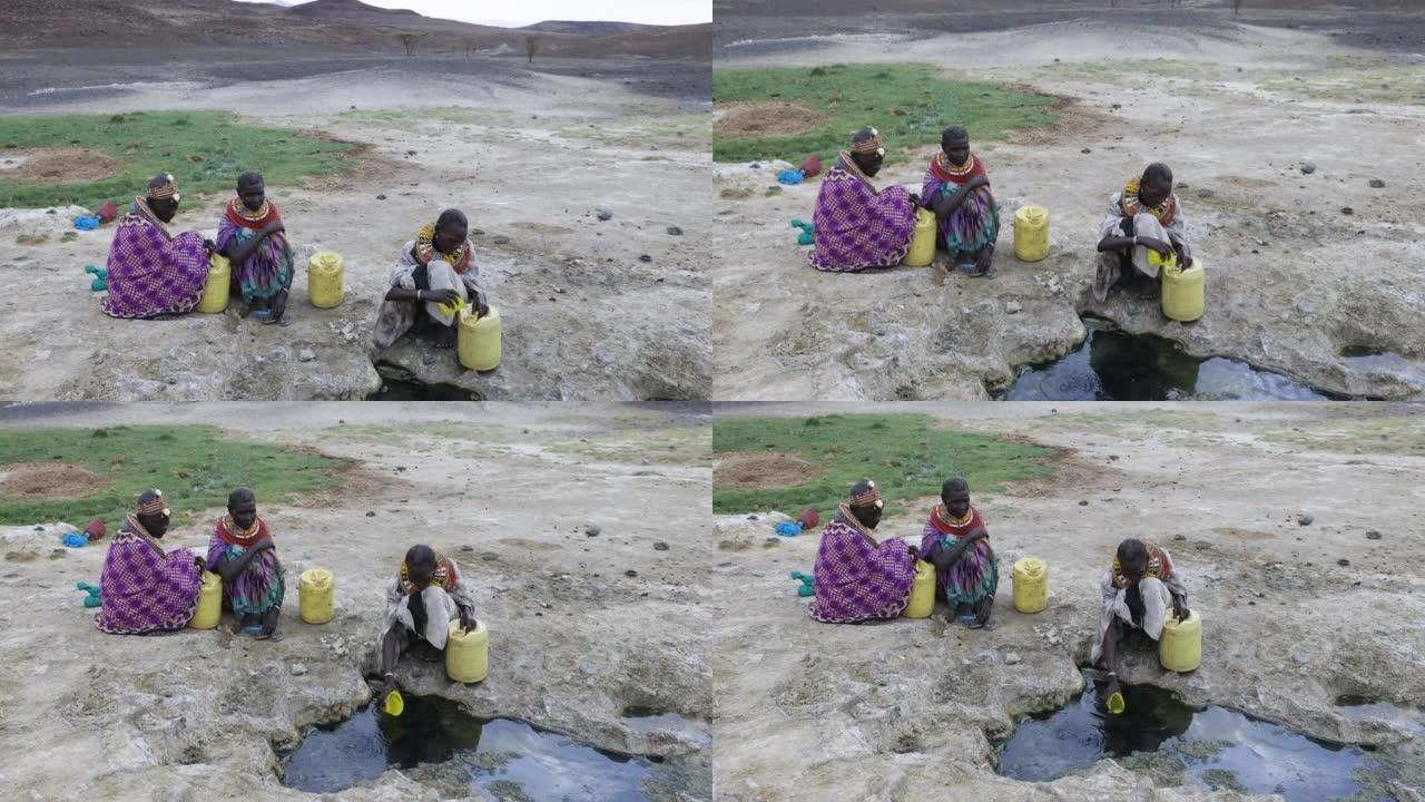 气候变化，干旱，水危机。倾斜特写视图。非洲妇女从肯尼亚图尔卡纳地区的火山泉水中收集塑料容器中的水