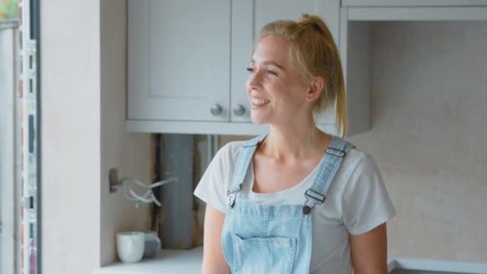 穿着工作服的微笑女人的肖像在家里翻新厨房-慢动作拍摄