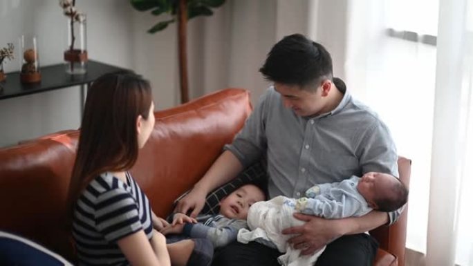 周末有两个孩子的亚洲华人家庭在客厅坐在沙发上