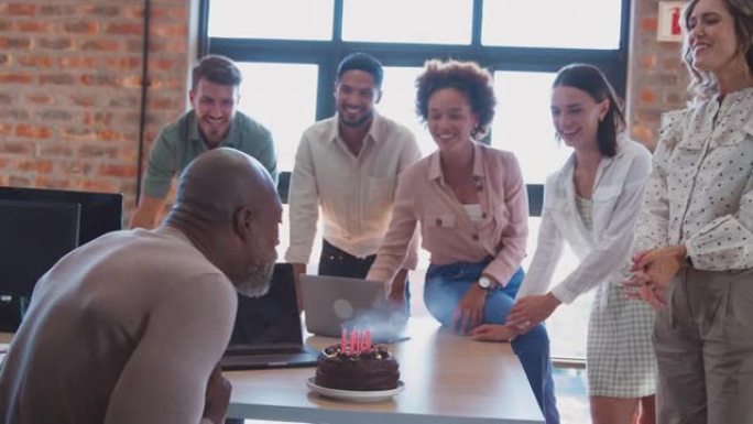 员工在多元文化办公室用蛋糕庆祝男同事的生日