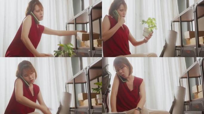亚洲妇女在忙于家庭办公室的房间安排时通电话