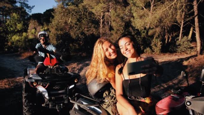 朋友微笑着在四轮摩托车冒险中使用智能手机自拍
