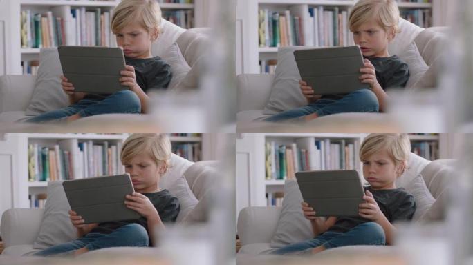 快乐小男孩使用数字平板电脑玩游戏在家沙发放松儿童在线浏览移动设备技术反社交成瘾概念4k