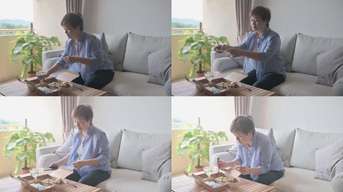 亚洲中国妇女在客厅用智能手机拍照外卖食物马来西亚食物nasi kerabu