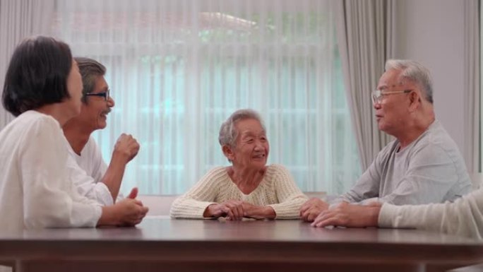 一群60-70岁的亚洲活跃老年人在疗养院交谈并度过了一段美好的时光。社会老年人