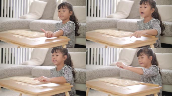 小女孩在家里的客厅玩和学习字母木制玩具