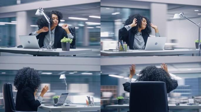 360学位办公室: 黑人女商人坐在办公桌前跳舞和微笑。美丽的女性专家在笔记本电脑上庆祝成功的电子商务