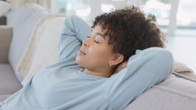 非裔美国妇女在家里的客厅沙发上深呼吸放松。一名年轻女子在休息室舒适的沙发上休息，周末独自享受休息日。